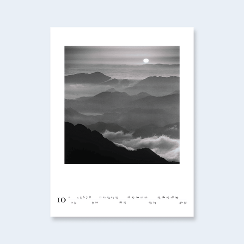 A minimalist calendar page featuring a misty mountain landscape with a sun over the horizon.