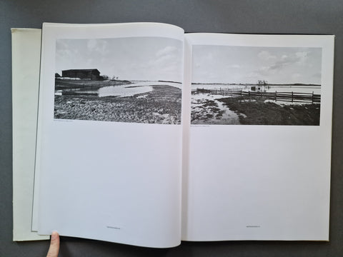 An open book, showing two printed black-and-white landscape photographs spread across the pages.