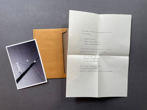 A folded white letter with printed text lies on a dark gray surface next to a brown envelope and a small black-and-white photograph.