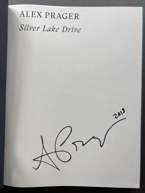 A signed copy of Alex Prager's 'Silver Lake Drive' book, featuring a black ink signature and the year '2013' on the white cover.