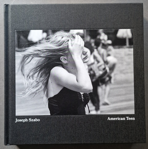 A hardcover book with a black textured cover and a central black-and-white photograph showing a young woman with windblown hair. The cover text reads 'Joseph Szabo' and 'American Teen'.