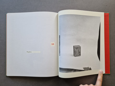 An open book, showing a black and white photograph of a small concrete block on the right page.