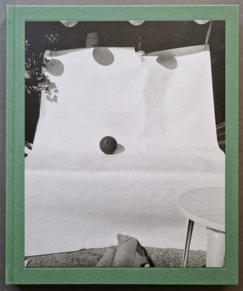 A book cover featuring a black and white photograph of a studio setup with a white backdrop, a small dark spherical object, and a pale green border around the edges.