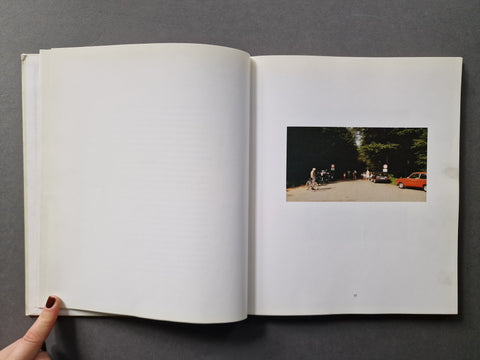 An open book: The right page features a small rectangular photograph showing a tree-lined street with a cyclist and an orange car.