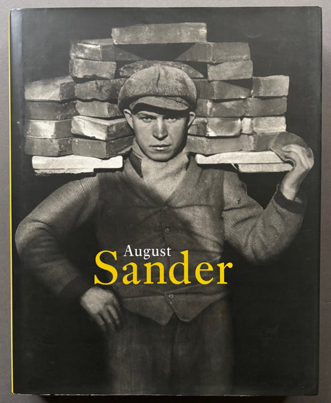 Book titled 'August Sander' with a cover featuring a black and white image of a builder carrying bricks on his shoulders.