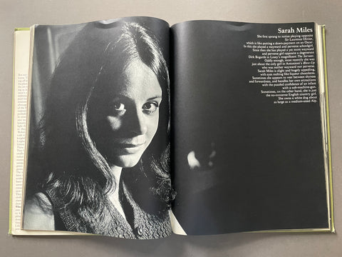 An open book showing a black-and-white portrait of Sarah Miles on the left page and printed text on the right page, photographed from above on a neutral surface.