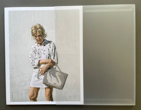 A square book cover featuring a photograph of a woman in a white patterned shirt and skirt holding a gray woven handbag, displayed against a dark gray background.