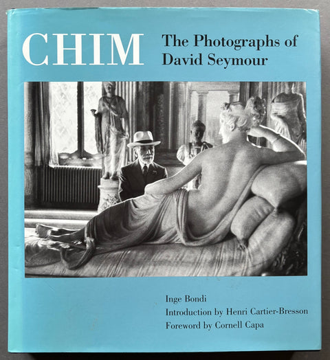 Book titled 'Chim: The Photographs of David Seymour' by David Seymour with a blue cover featuring the image of David Seymour sitting across from a statue of a woman on a bed.
