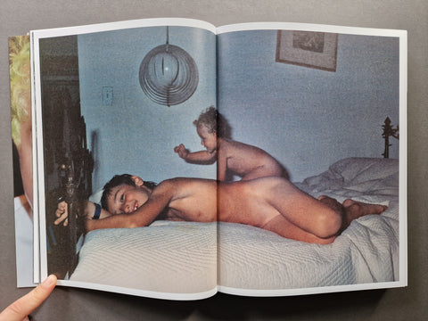 An open book showing a photographic print of two children on a bed in a dimly lit room.