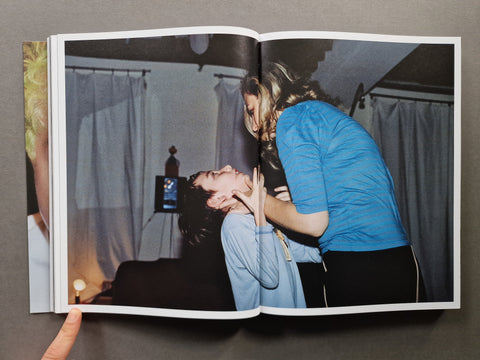 An open book, showing a printed photograph of two people in an indoor scene - mother and child.