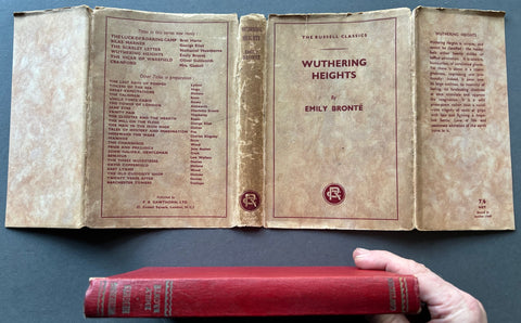 Book titled 'Wuthering Heights' by Emily Bronte with a red cover and a beige dust jack with red type.