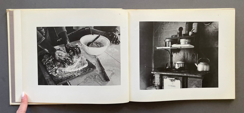 An open photo book or photo album laid flat on a dark gray surface, showing two black-and-white printed photographs on cream pages.