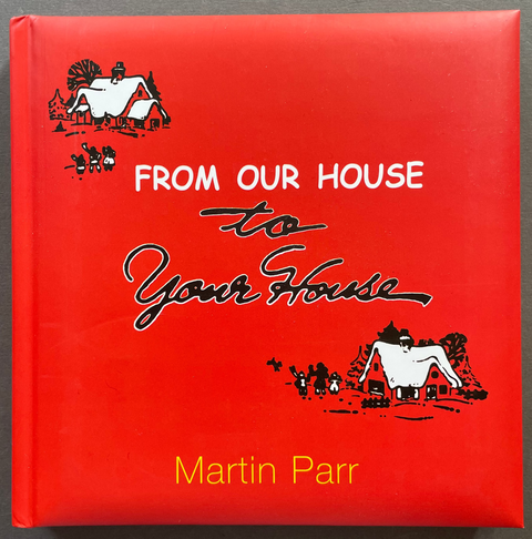 The book cover of 'From Our House to Your House' by Martin Parr, featuring a bright red background with white and black illustrations and text, photographed flat on a dark gray surface.