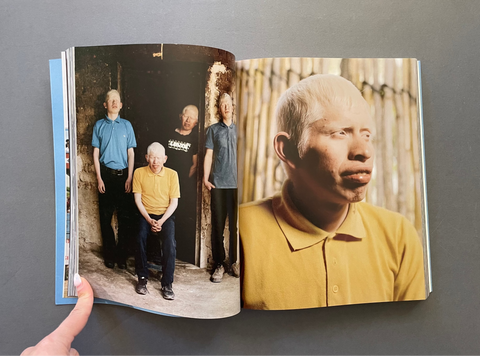 An open photo book or magazine laid flat on a dark gray surface, showing two printed photographs on the pages.