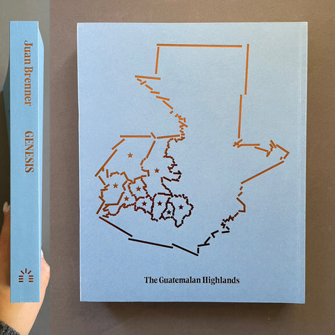 A book titled 'The Guatemala Highlands' by Juan Brenner, showing the front cover with a light blue background and an orange map outline, alongside the book spine on a brown surface.