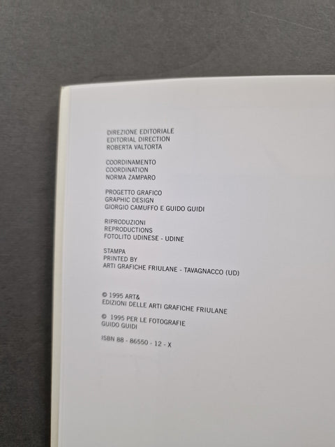 A close-up of an open book or booklet showing printed Italian copyright text on a white page, photographed against a dark gray background.