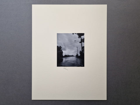 An off white mount with a centered black and white original silver gelatin print with the letter F hand-written right below the print.