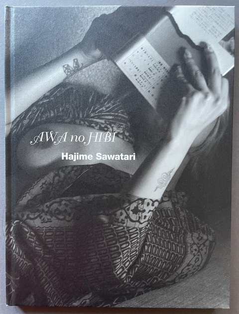 Book cover with a black and white image of a person's arm with tattoos holding a book, titled 'AWA no JIBI' by Hajime Sawatari.