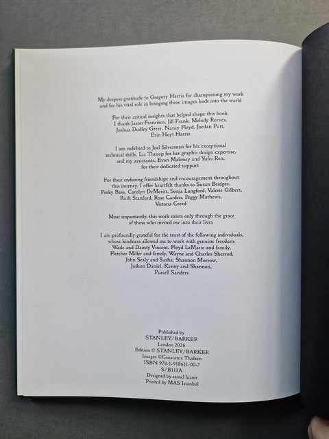 An open book showing printed text on a white page, photographed from above on a dark gray surface.