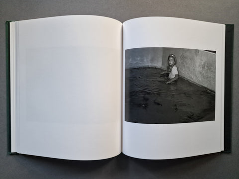 An open book, showing a black-and-white photograph printed on the right page. The left page is blank, and the book has a dark green cover edge visible along the sides.