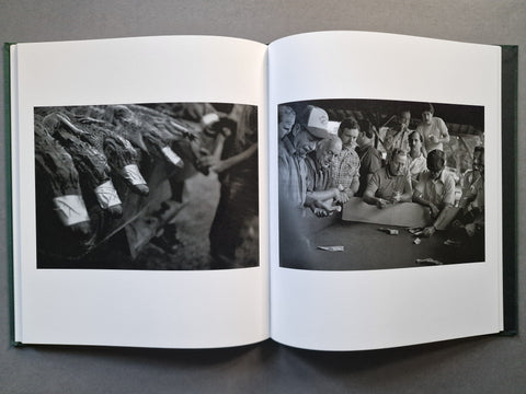 An open hardcover book laid flat on a dark gray surface, showing two black-and-white photographic pages spread side by side.