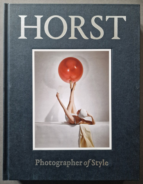 The book cover of Horst: Photographer of STyle in navy blue with a photo of a woman in white swimwear balancing a red ball with her feet in the air.