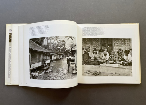 An open book spread showing two black-and-white historical photographs printed on white pages, photographed from above on a dark gray surface.