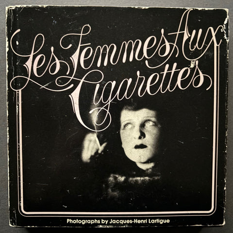 Book titled 'Les Femmes aux Cigarettes' by Jacques-Henri Lartigue with a black cover featuring an image of a woman holding a cigarette.