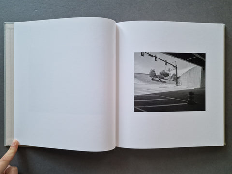 An open book, showing a mostly blank white left page and a black-and-white street scene printed on the right page.