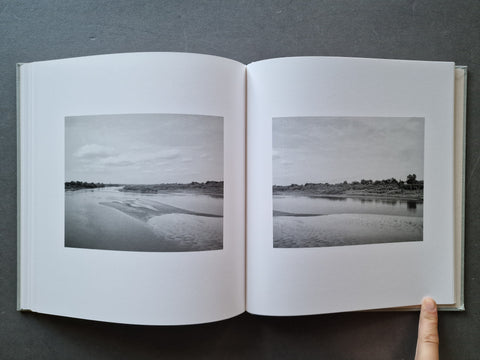An open hardcover book, showing two black-and-white landscape photographs printed on the pages.