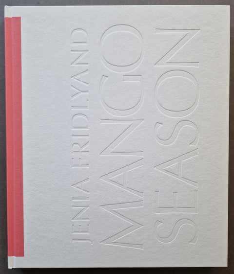 A hardcover book titled 'Mango Season' by Jenia Fridlund, featuring a textured off-white cover with embossed lettering and a contrasting pink spine band.