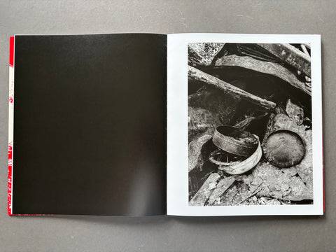Open book showing a black and white photograph of broken pots on a gray surface