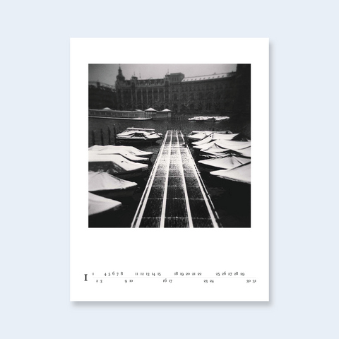 A minimalist calendar page featuring a central architectural photograph with a long perspective path.