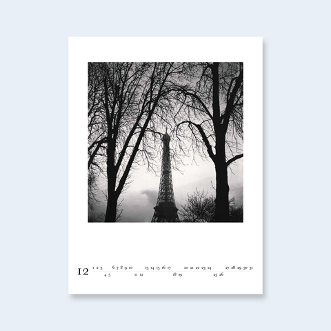A minimalist calendar page featuring a photograph of the Eiffel Tower framed by bare winter trees.