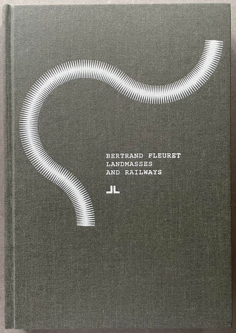 A hardcover book titled 'Bertrand Fleuret Landmasses and Railways' with a textured dark gray-green cover, featuring a white wavy line graphic and white typography, photographed flat on a neutral gray surface.