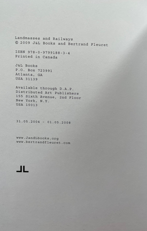A close-up of a white printed book or publication page with black text, including the title 'Landmasses and Railways' and publisher information for J&L Books and Bertrand Fleuret, photographed against a dark surface.
