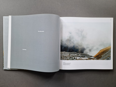 An open book spread showing a landscape photo of misty mountains on the right page