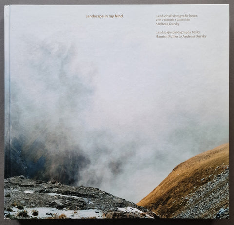 A square book cover titled "Landscape in my Mind" featuring a misty mountain landscape photograph with snow, dark rocky slopes, and a grassy hillside. Small brown text appears at the top right, and the book is photographed against a dark background.