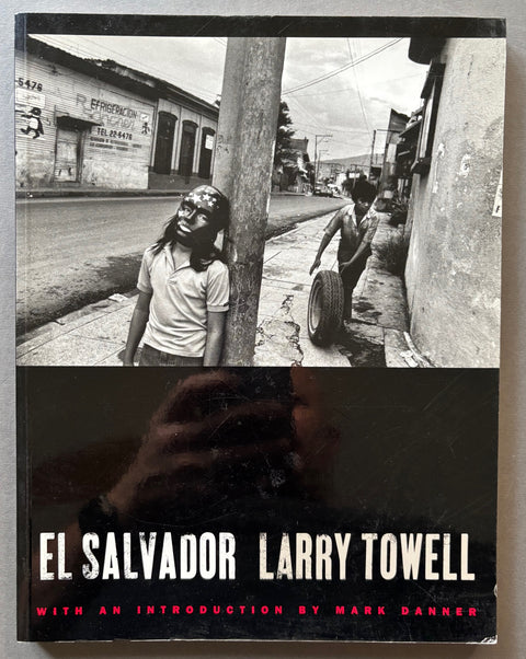 Book titled 'El Salvador' by Larry Towell with a black cover including a photograph of boy leaning against a post and another boy wheeling a tyre along the street.