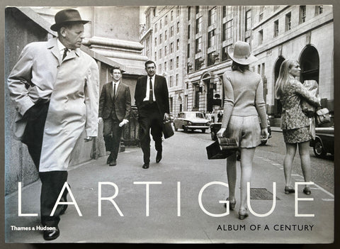Book titled 'Lartigue: Album of a Century' by Jacques Henri Lartigue with a cover featuring a black and white image of people walking along a street.
