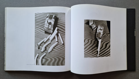 An open book showing two black-and-white photographic panels of distorted boxes of Camel cigarettes