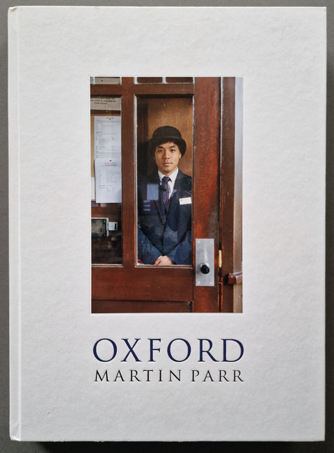 The book cover of 'Oxford' by Martin Parr, featuring a white textured background with a central photograph of a man in a uniform behind a wooden door, and the title and author name printed below.