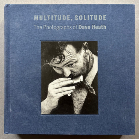 Book titled 'Multitude, Solitude: The Photographs of Dave Heath' with a blue cover and an image of a man playing a harmonica.