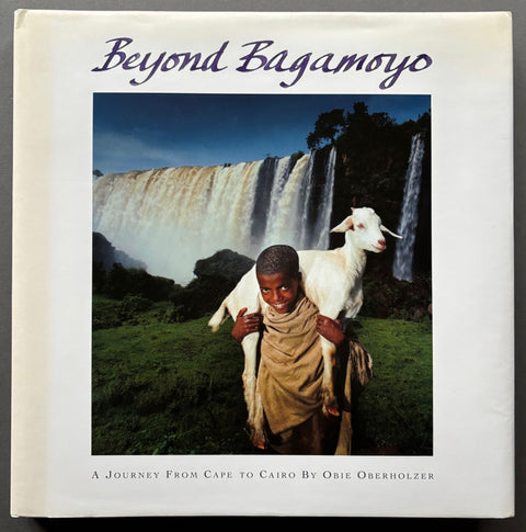 Book titled 'Beyond Bagamoyo: A Journey From Cape to Cairo' by Obie Oberholzer with a white cover featuring the image of a boy carrying a goat on his shoulders.