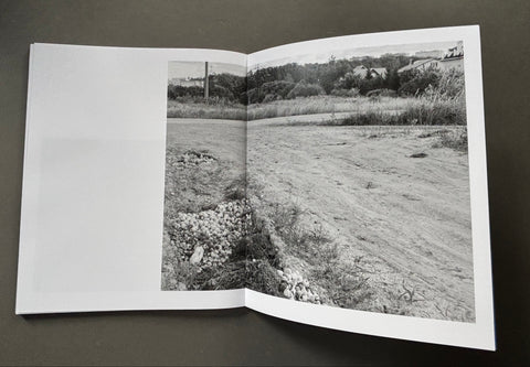 Open book showing a black and white photograph of a field on a dark background