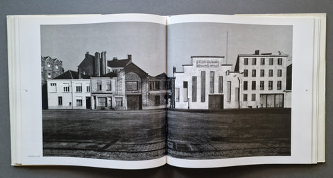 An open book showing a black-and-white architectural photograph printed across both pages, with buildings and a street scene visible in grayscale.