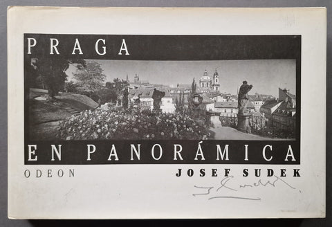 A vintage book cover for 'Praga en Panorámica' by Josef Sudek, published by Odeon. The cover features a black and white panoramic photograph of Prague with a white border