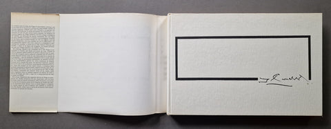 An open book or art print with blank white pages, featuring a black rectangular border on the right page