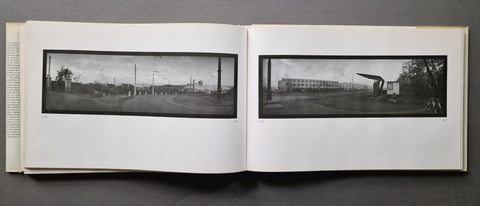 An open book spread, showing two wide black-and-white panoramic photographs mounted on white pages against a dark gray background.