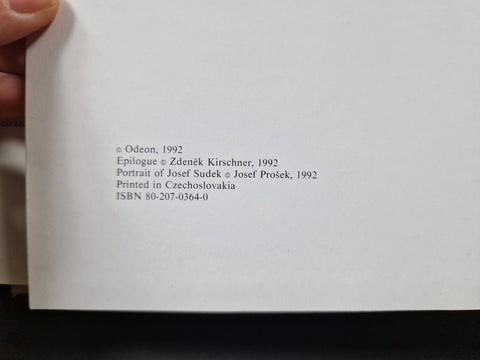 A close-up of a book's printed copyright page held by a hand, showing publication details and ISBN in black text on white paper.